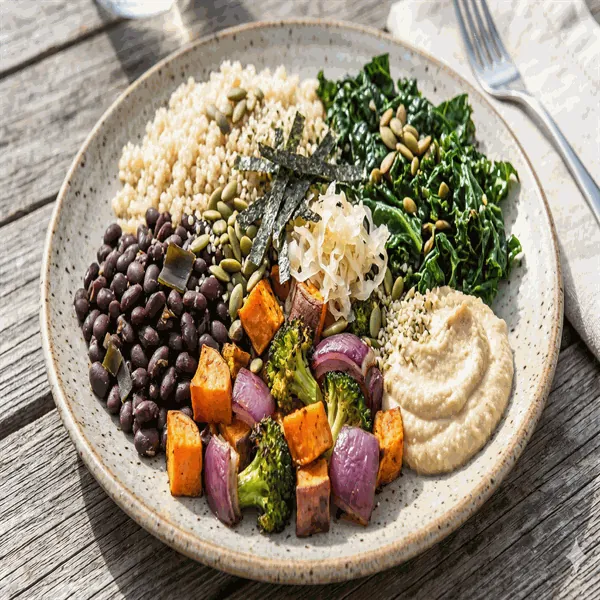 Vegan Buddha bowl with quinoa, black beans, roasted vegetables, massaged kale, hummus and seeds